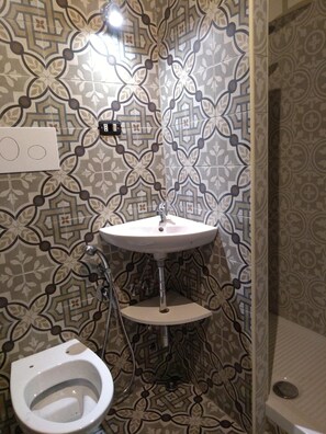 A bathroom with a patterned tile wall, a pedestal sink, a toilet, and a shower. - B&B La Marchesa (Sant'Anastasia)