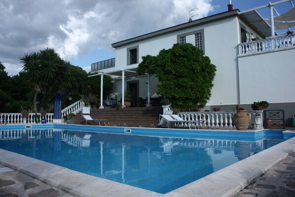 A swimming pool with a white house in the background. - B&B La Marchesa (Sant'Anastasia)