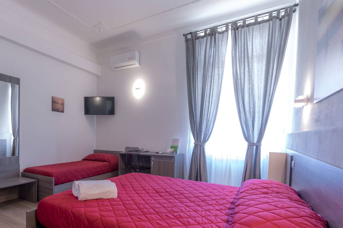 Un dormitorio con dos camas, televisión, escritorio y armario.