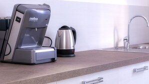 Een moderne keuken met een koffiezetapparaat, waterkoker en een roestvrijstalen spoelbak.