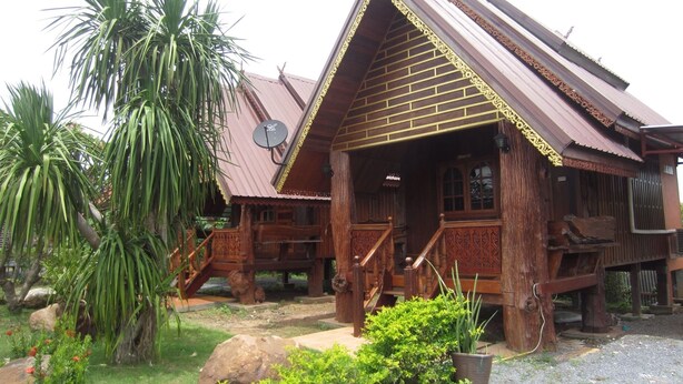 A traditional wooden house with a sloped roof, a satellite dish, and a porch. - Pialo Resort (Na Klang)