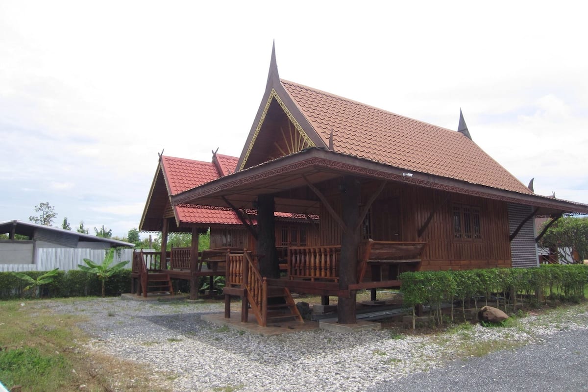A traditional wooden house with a tiled roof and a porch.