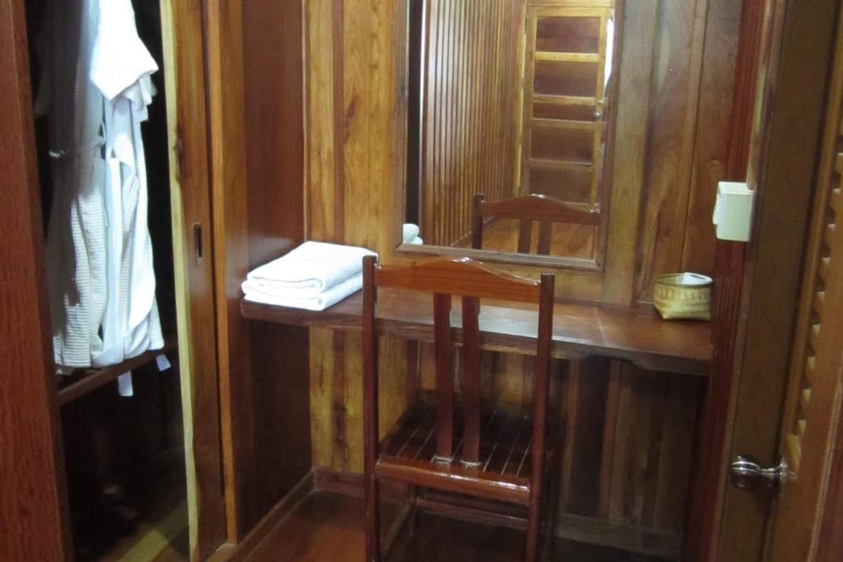 A wooden room with a wooden wardrobe, a chair, and a small table.