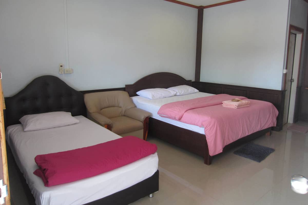A hotel room with two beds, a chair, and a door.