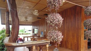 A wooden interior with a high ceiling, hanging floral arrangements, and a tiled floor. - Pialo Resort (Na Klang)