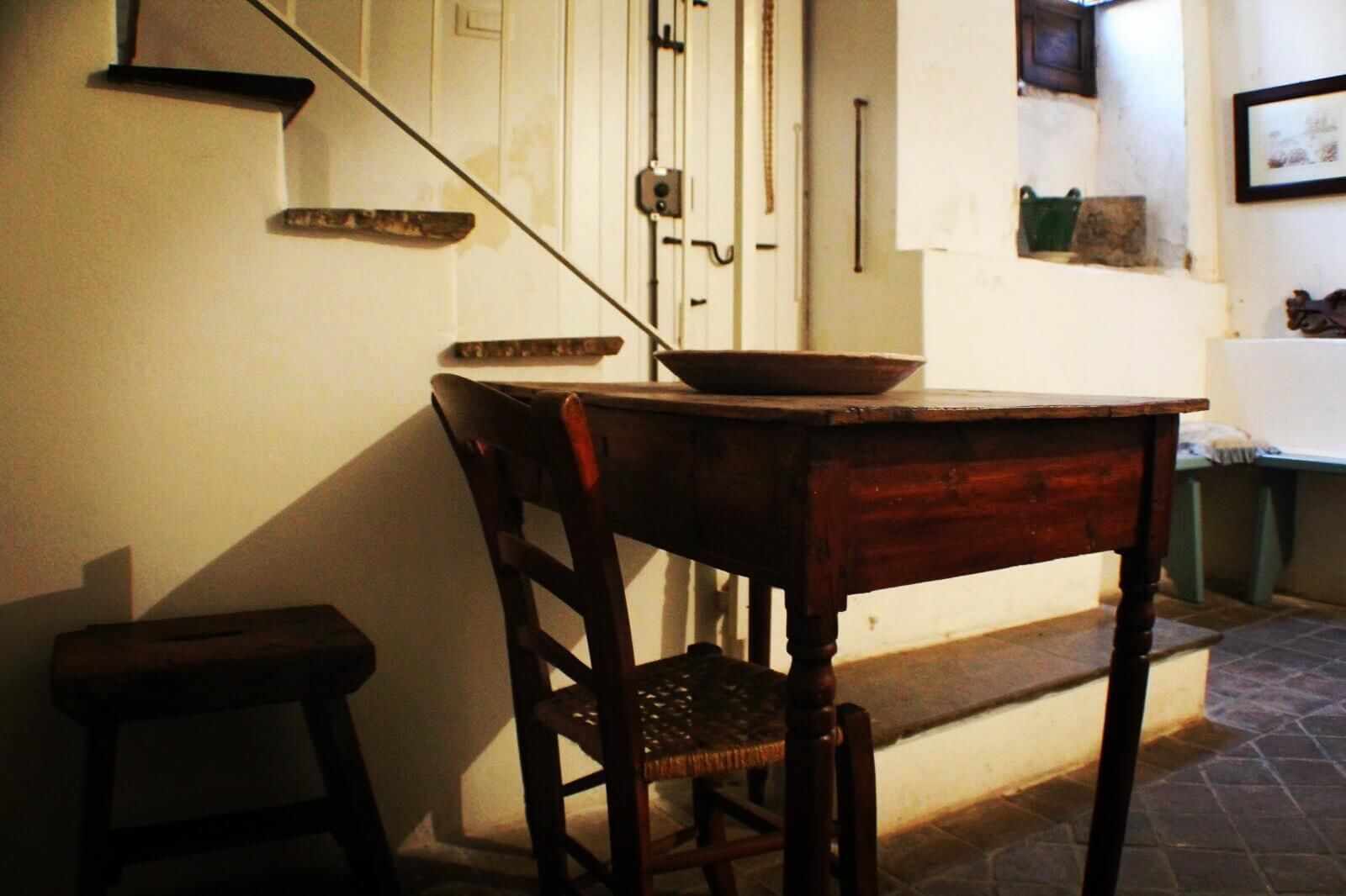 Un tavolo da pranzo in legno con una ciotola sopra, una sedia e uno sgabello.