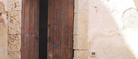 A wooden door with a metal latch, set in a stone wall with a small vent.