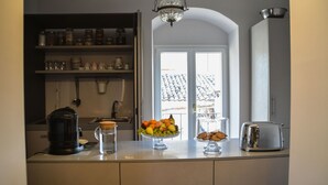 A kitchen with a fruit bowl, a coffee maker, a toaster, and a window with a view of a building. - ZIOLì (Noto)