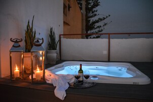 Un jacuzzi con velas y copas de vino en un balcón.