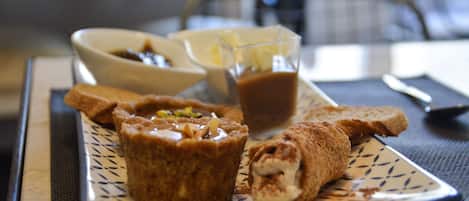 Un plato con un pastel, un vaso de líquido marrón y dos tazones de comida sobre una mesa.