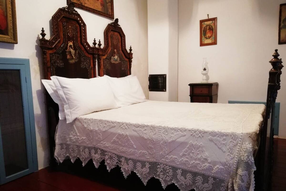 A bed with a white lace bedspread and a wooden headboard.