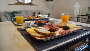 A breakfast table with toast, cheese, ham, and a fruit plate. There are two glasses of orange juice. - ZIOLì (Noto)