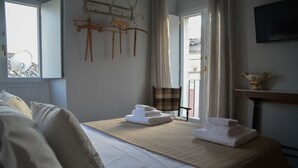 A hotel room with a bed, a table with towels, a chair, a television, and a window with curtains. - ZIOLì (Noto)