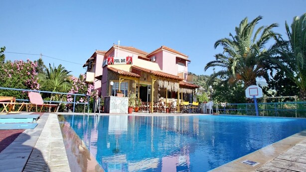 A pool area with a building labeled "POOL BAR" and outdoor seating. - Armonia Studios (Lesvos)