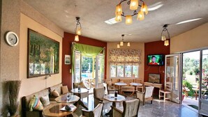 A cozy restaurant with wooden furniture, a large painting, and a TV on the wall. - Armonia Studios (Lesvos)
