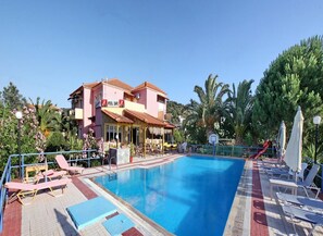 Una piscina al aire libre, sombrillas, sillones reclinables de piscina