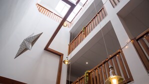 Un interior de varios niveles con barandas de madera, luces colgantes y una estrella decorativa en la pared.