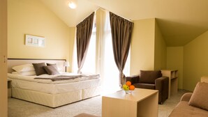 Un dormitorio con cama, sofá, mesa de centro y cortinas.
