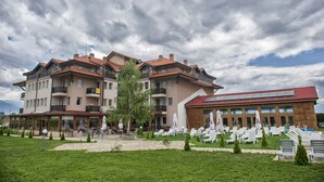 Un hotel de varios pisos con mesas al aire libre y una piscina.