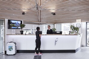 A reception desk with a modern design, a television mounted on the wall, and a potted plant on the counter. - Araslöv Golf & Resort (Färlöv)