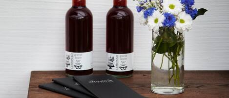 Two bottles of granat apple on a wooden table with a vase of flowers.