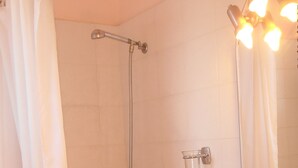 A bathroom with a shower, a sink, a glass soap dispenser, and a mirror. - Kipos Studios (Lesvos)