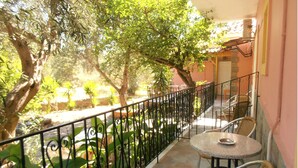 A balcony with a wrought iron railing, a small round table with a metal bowl, and wicker chairs. - Kipos Studios (Lesvos)