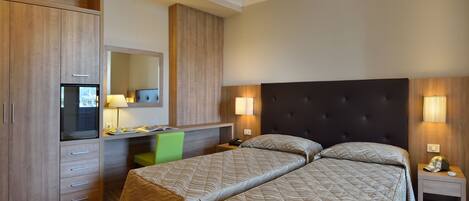 Una habitación de hotel con cama, escritorio, silla, armario y espejo.