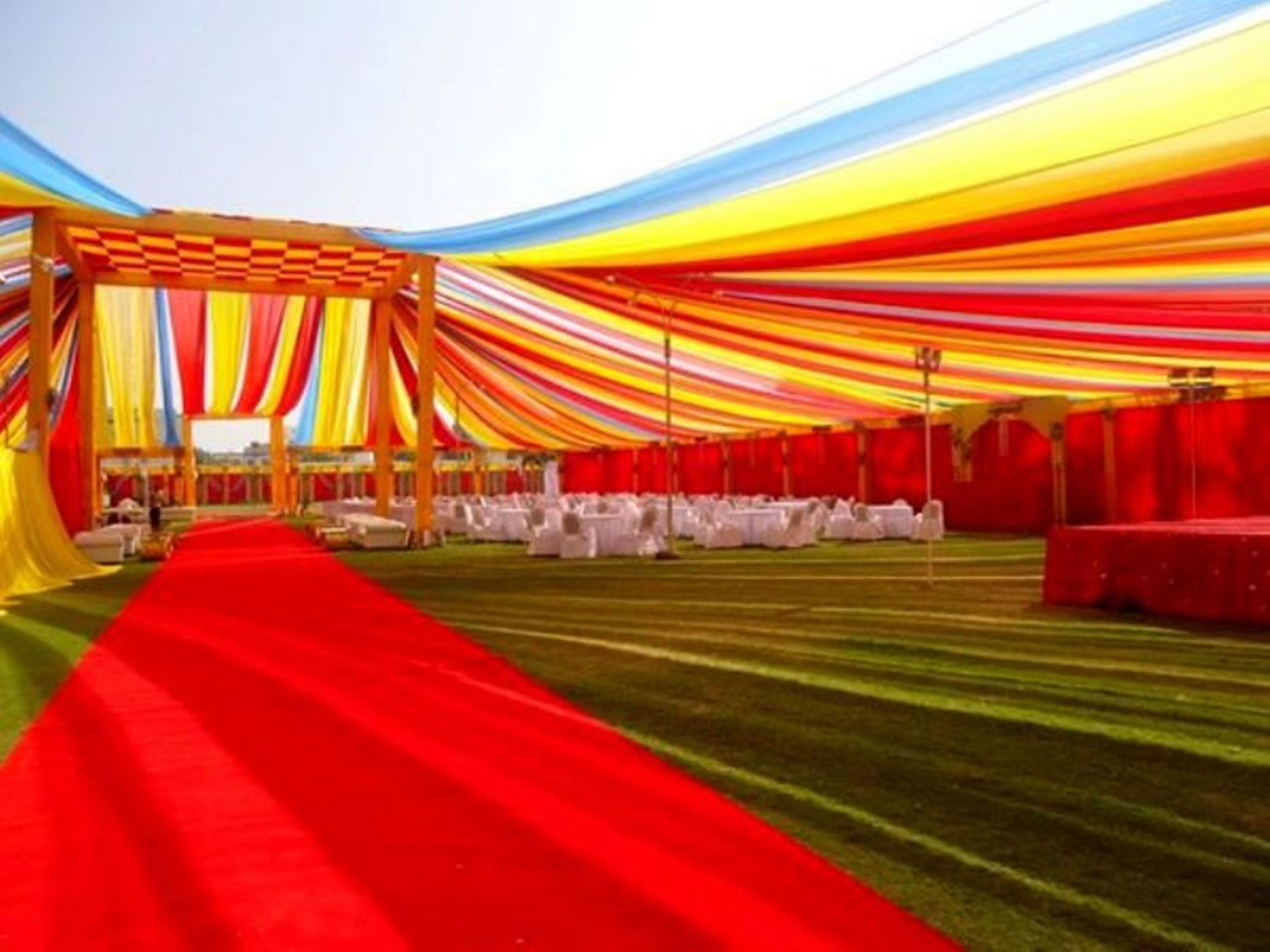 A tented event space with a red carpet and white tables.