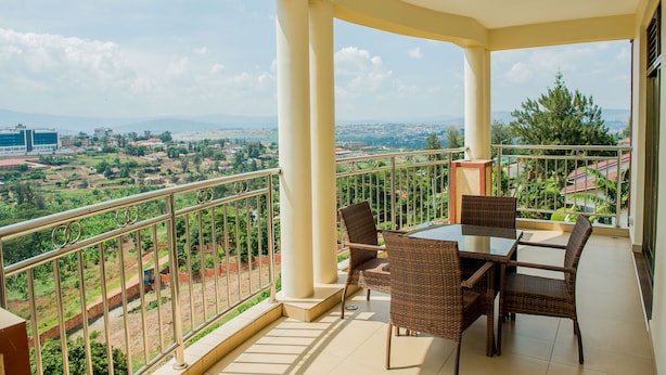 Ein Balkon mit Tisch und Stühlen mit Blick auf eine reizvolle Landschaft mit Gebäuden und Grünflächen.