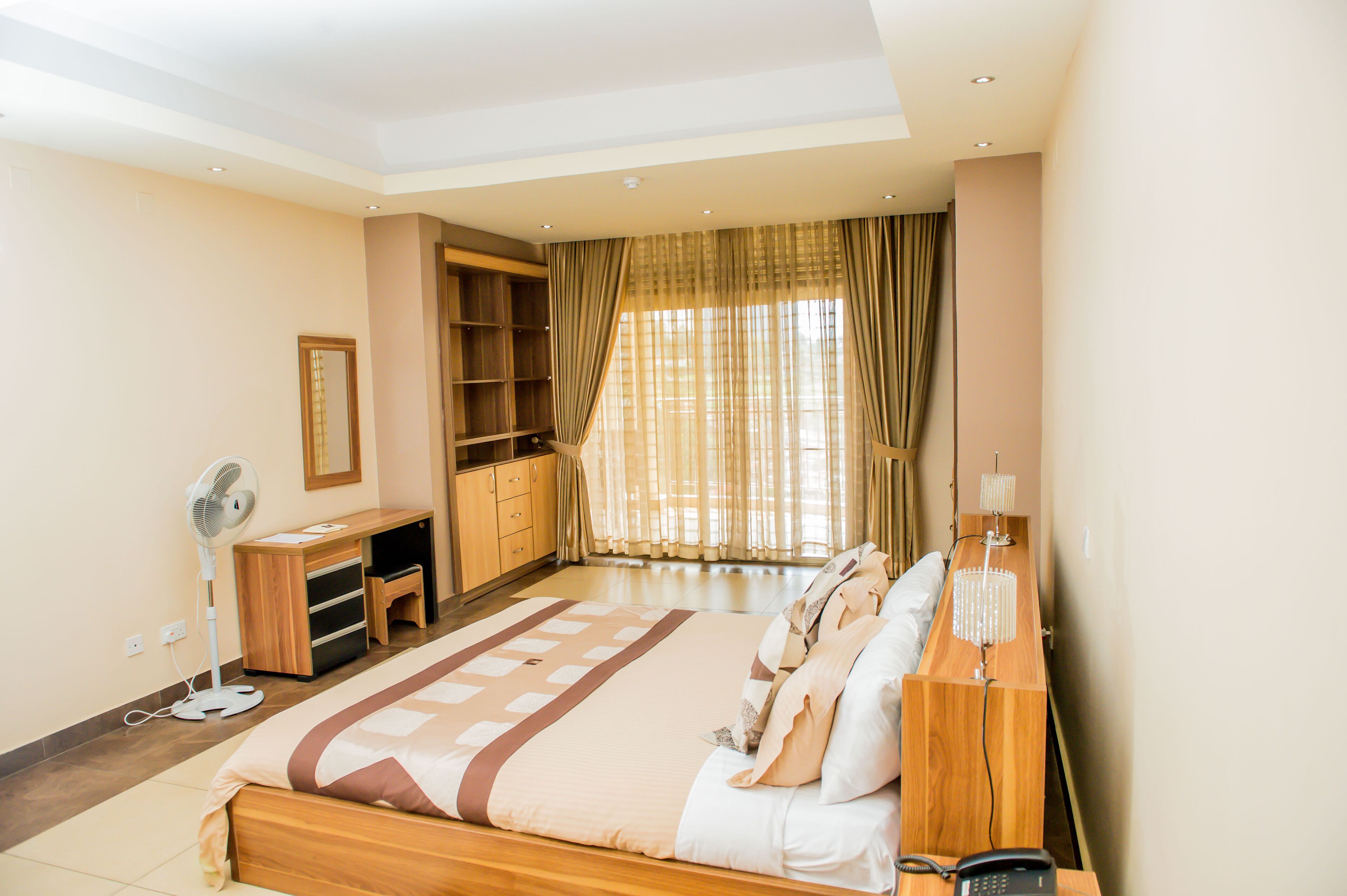 A bedroom with a bed, bedside table, lamp, and a desk with a chair.