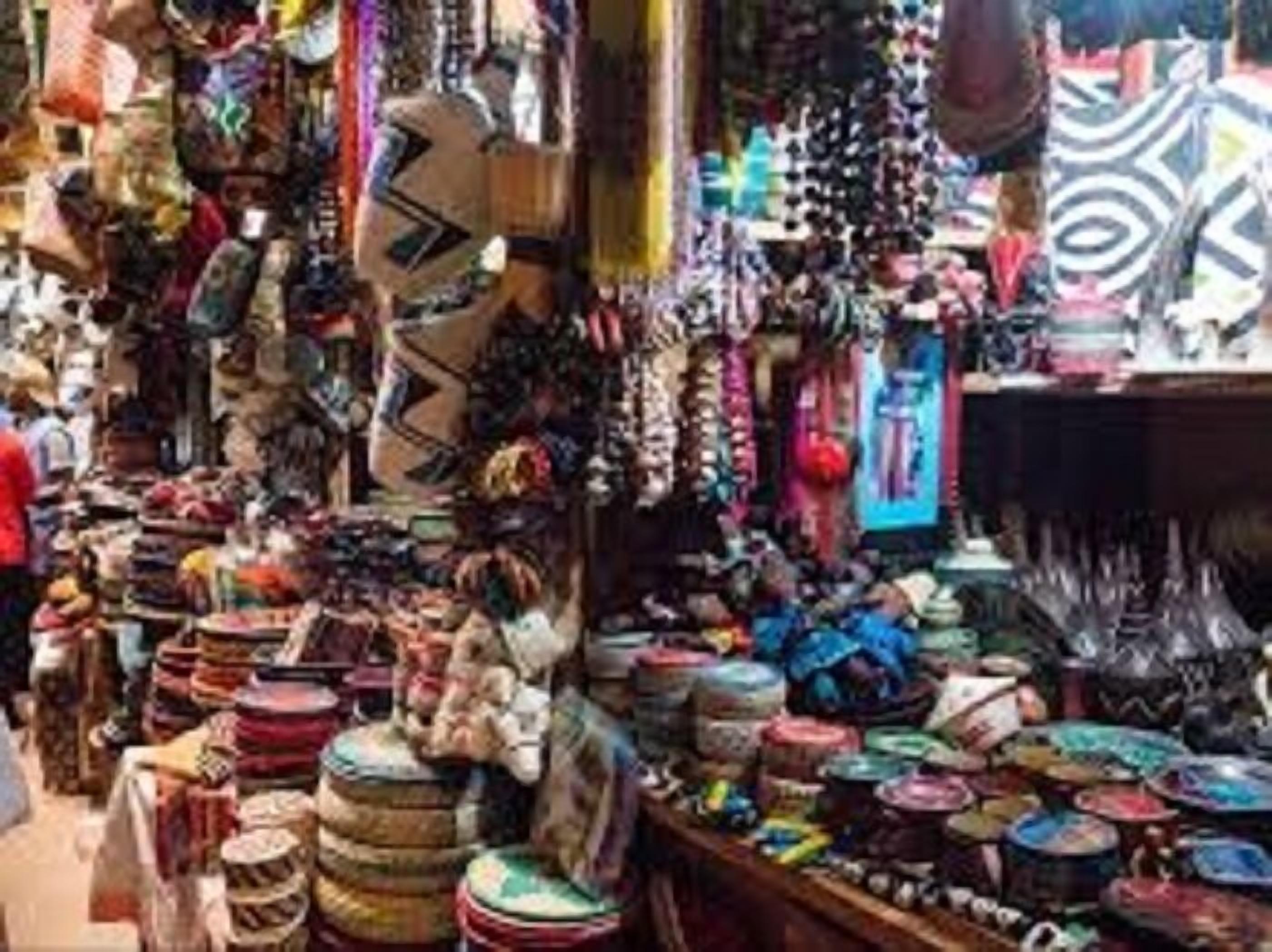 Un marché où l’on trouve divers étals vendant des textiles aux couleurs vives, de la poterie et d’autres articles.