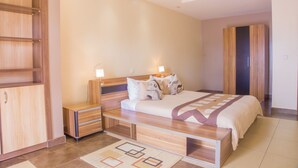 Ein modernes Schlafzimmer mit einem großen Bett, Nachttischen aus Holz und einem Kleiderschrank.