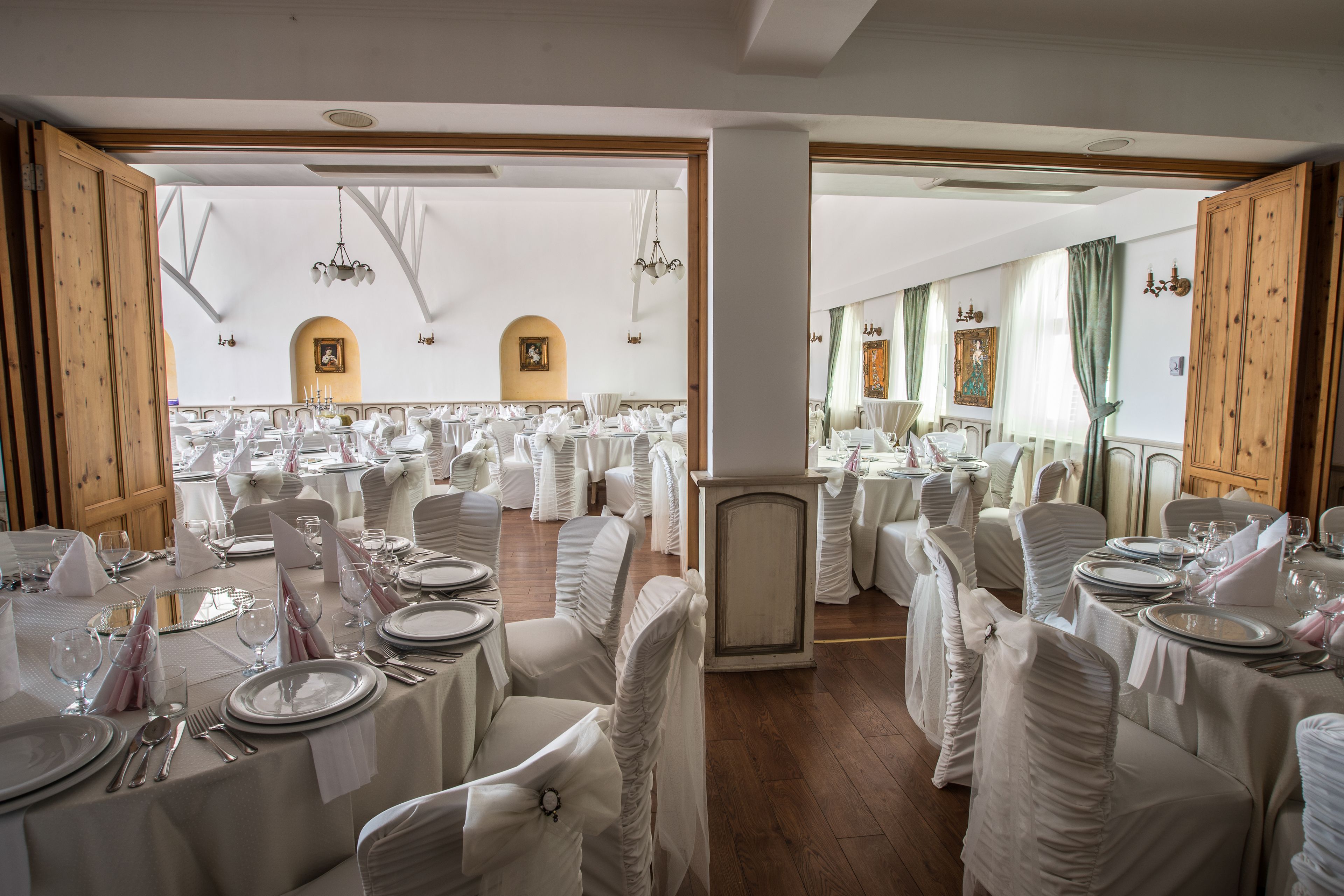 A banquet hall with round tables set for a formal event, featuring white tablecloths and chairs.