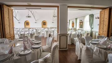 A banquet hall with round tables set for a formal event, featuring white tablecloths and chairs.