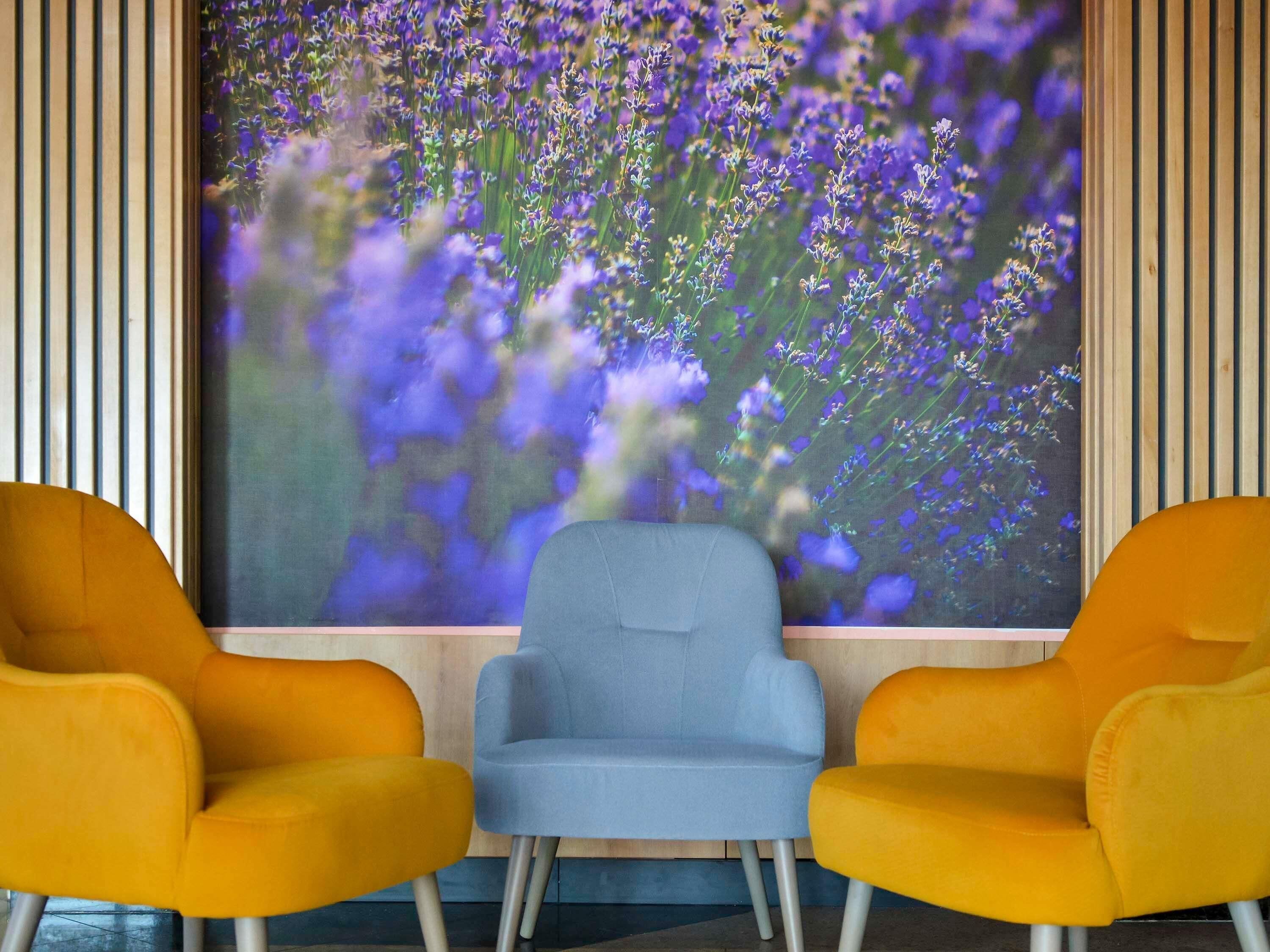 A room with two yellow chairs facing a large window displaying purple flowers.