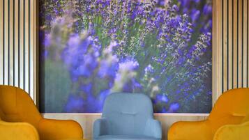 A room with two yellow chairs facing a large window displaying purple flowers.