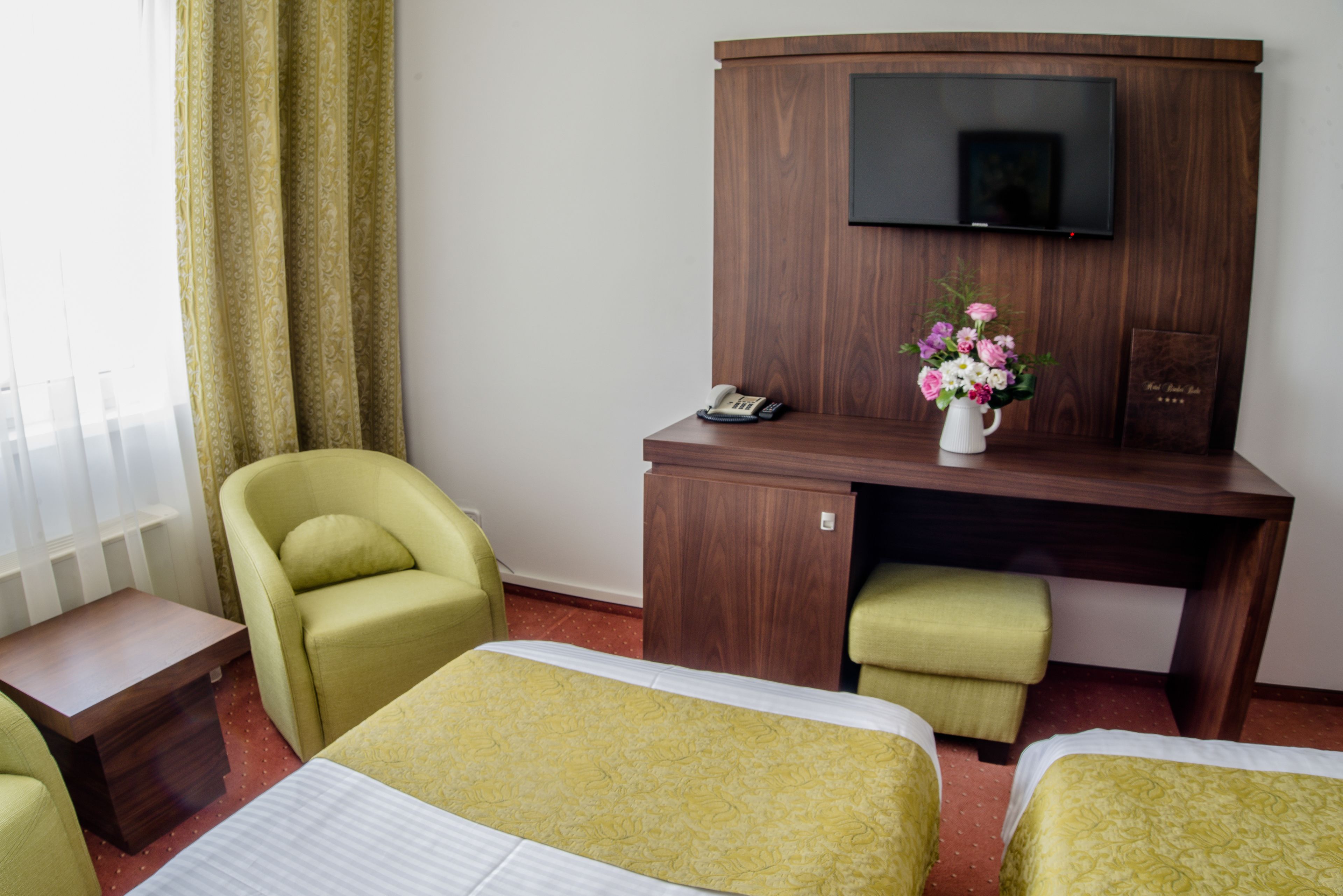 Una habitación de hotel con dos camas, un escritorio, una silla, un televisor y un teléfono.