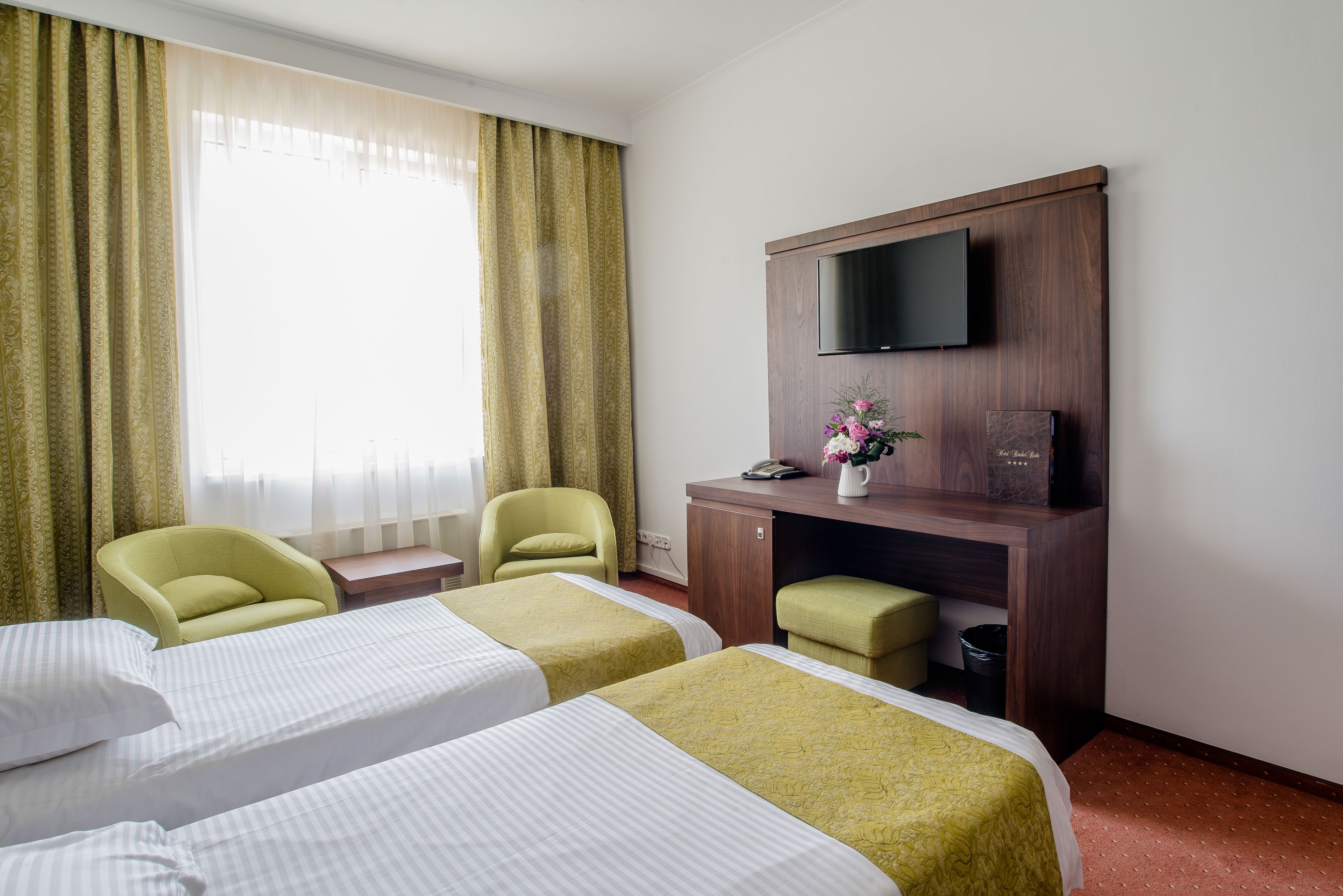 Habitación de hotel con dos camas, un escritorio, televisión de pantalla plana, una silla y una mesita.