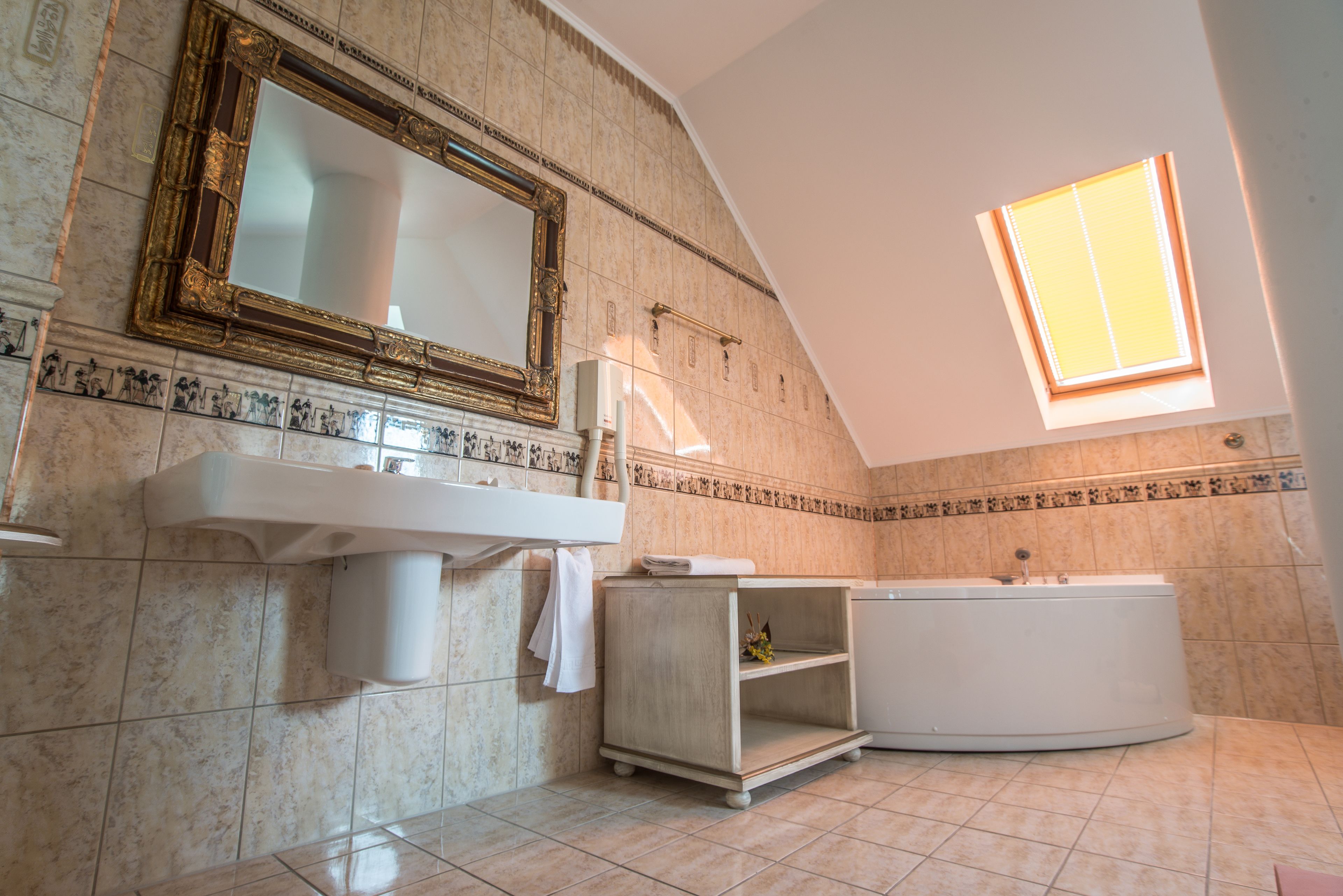 A bathroom with a large mirror, a sink, a bathtub, and a skylight.