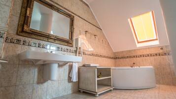 A bathroom with a large mirror, a sink, a bathtub, and a skylight.