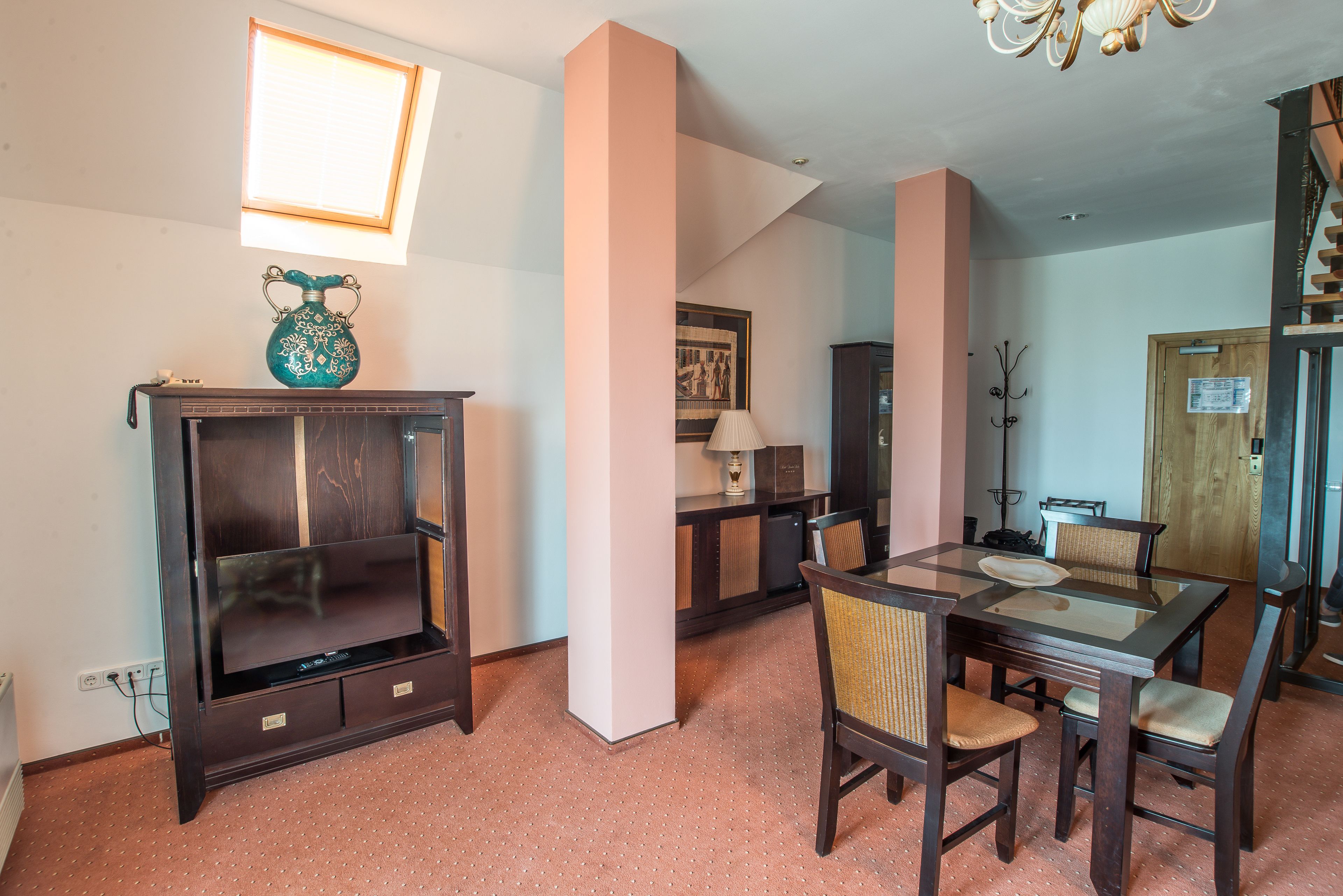 A dining area with a wooden table and chairs, a cabinet, and a chandelier.