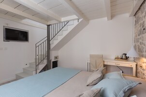Un dormitorio con cama, escritorio, silla, ventana y escalera.