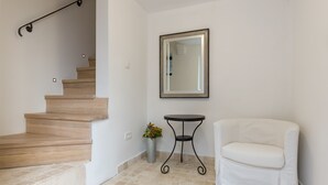 A staircase with wooden steps, a small table with a metal frame, a white chair, and a mirror on the wall. - Dubrovnik Sweet House (Dubrovnik)
