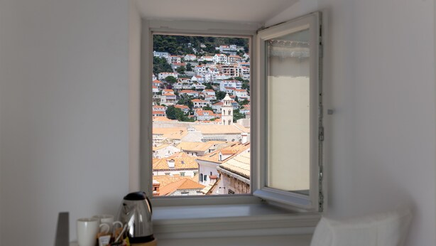 A room with a window overlooking a densely packed urban area with red-roofed buildings. - Dubrovnik Sweet House (Dubrovnik)