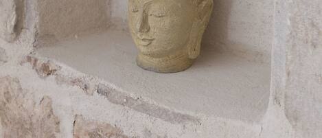 Escultura de cabeza de Buda de piedra en un nicho dentro de una pared de piedra.