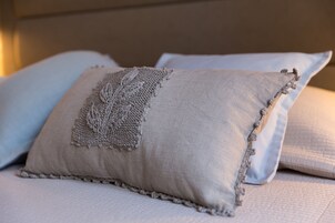 Uma cama com um travesseiro bege com textura e um travesseiro branco.