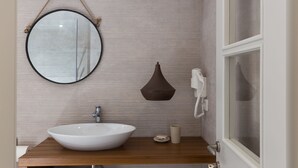 A bathroom with a wooden vanity, a round mirror, a white sink, a towel rack, and a shower door. - Dubrovnik Sweet House (Dubrovnik)