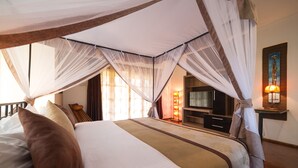 A bedroom with a canopy bed, a television, and a nightstand with a lamp. - Ameg Lodge Kilimanjaro (Moshi)