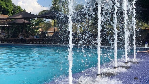 A swimming pool with multiple water jets shooting up from the floor. - Ameg Lodge Kilimanjaro (Moshi)